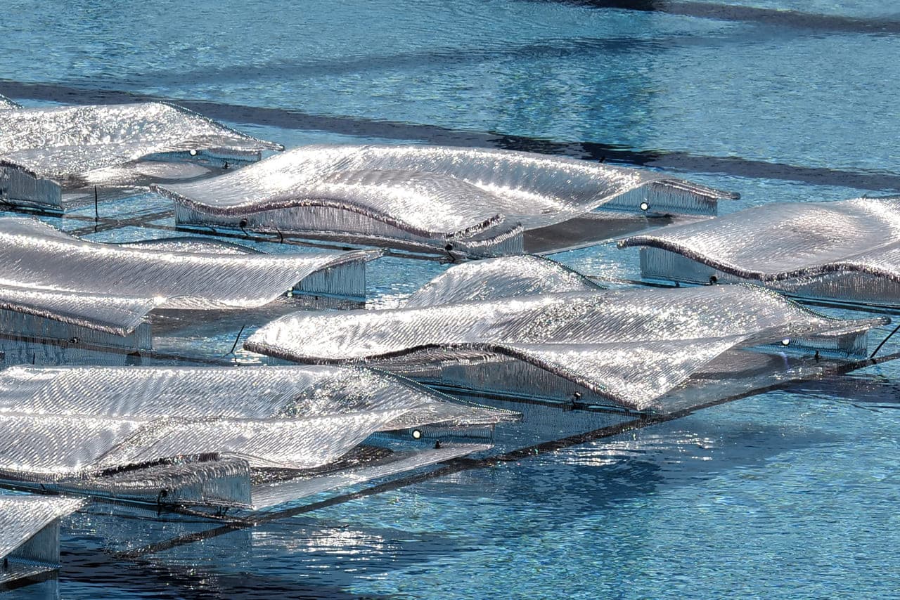 Final Sparkling installation with reflective rippled surfaces floating over water.