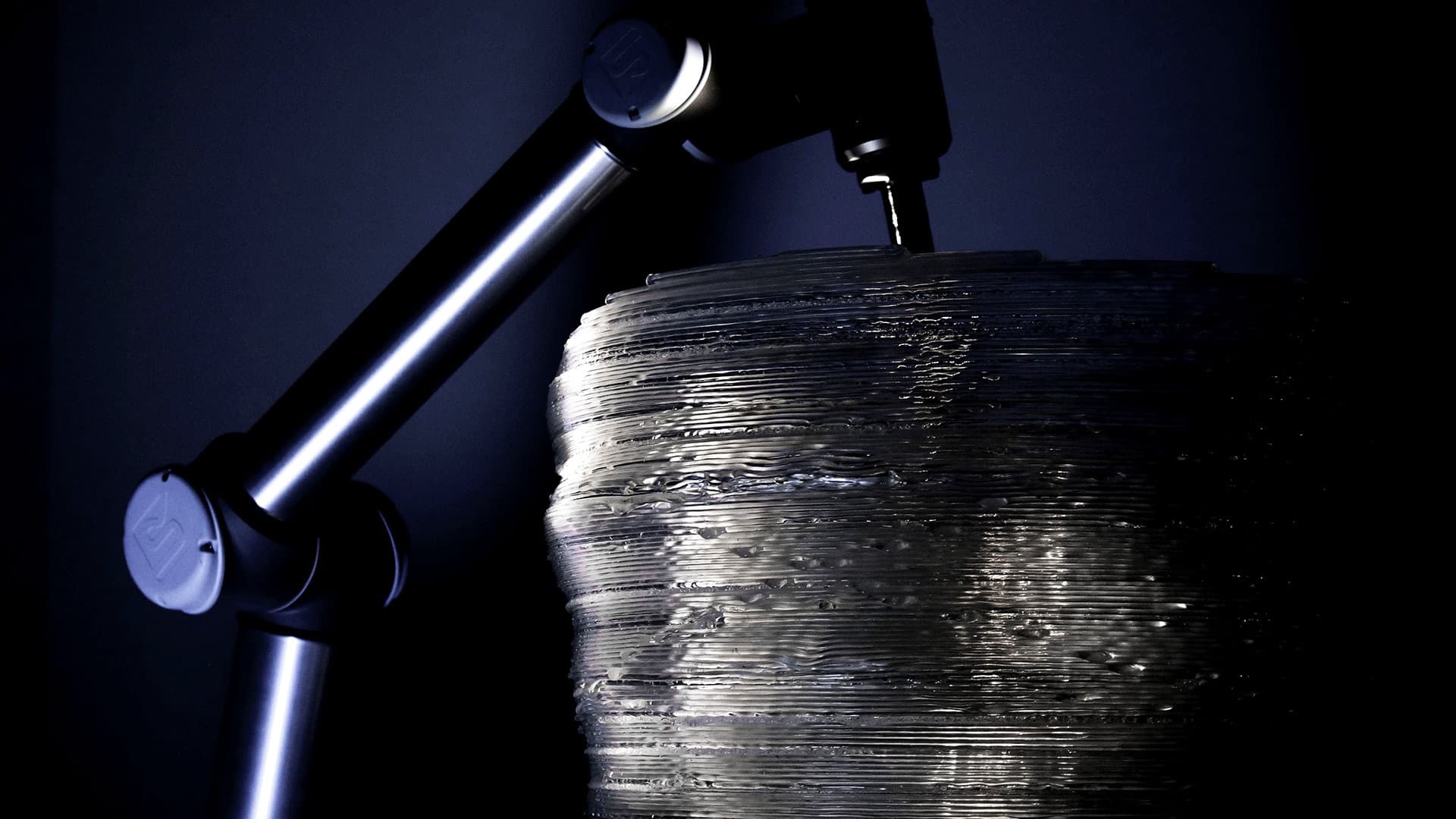 Robotic arm extruding transparent PLA onto a large printed form.